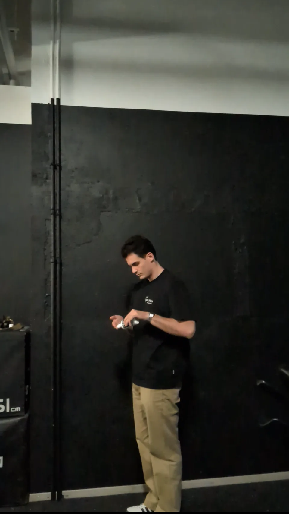 Applying chalk to the fingertips beside a dark measuring wall